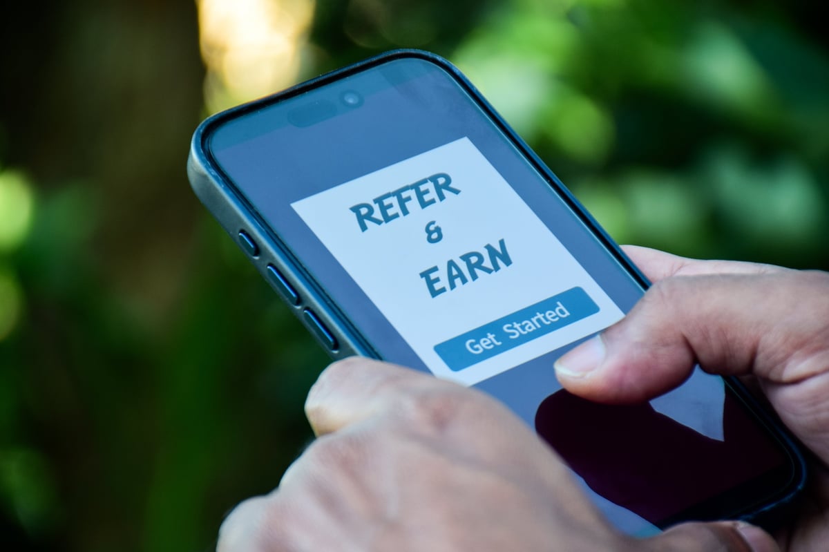 Smartphone displaying refer and earn program. Referral program to make money marketing strategy concept.