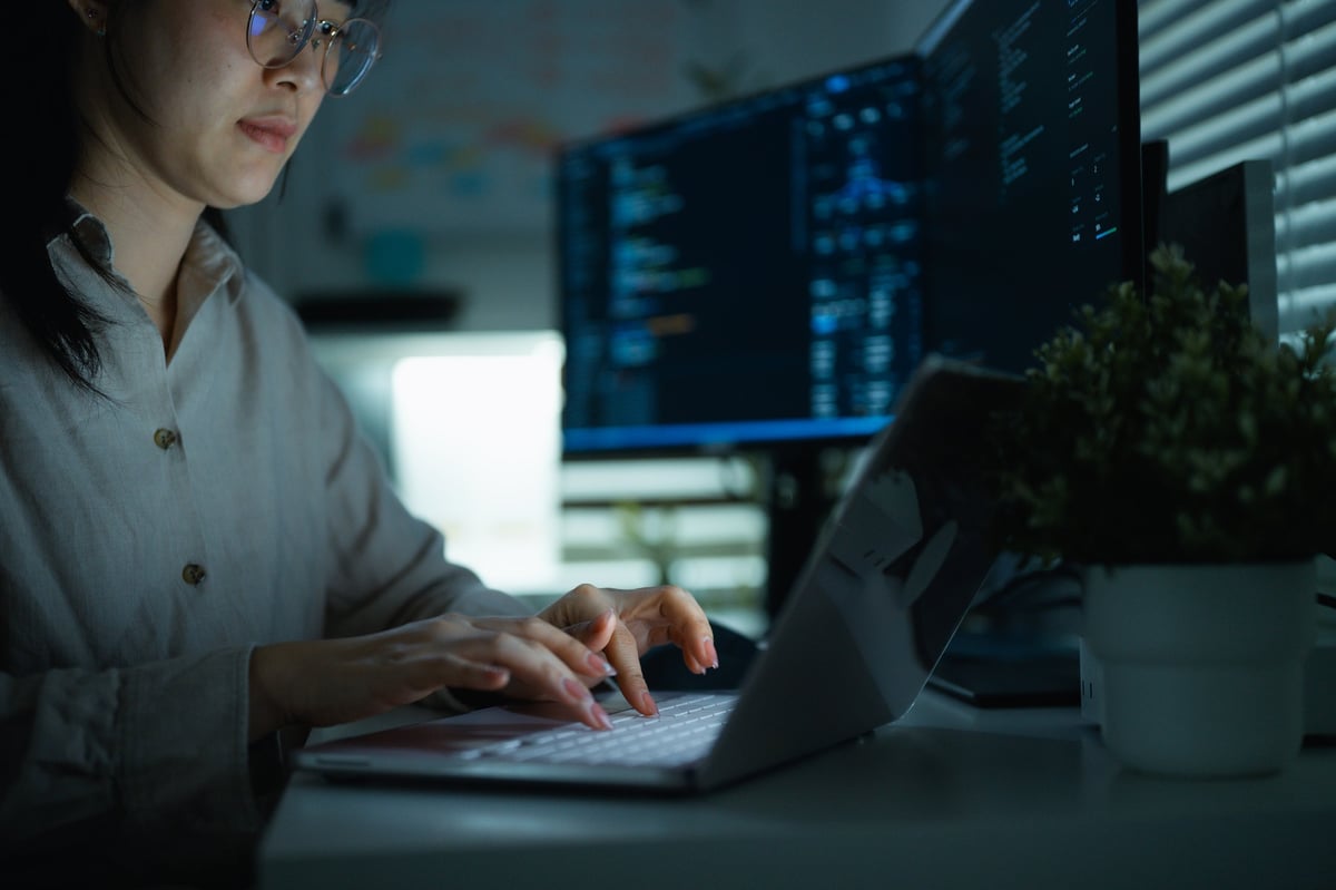 Coding image of a typing engaged in software development. Types with both hands on a laptop keyboard. The image presents a focused professional technology workplace with computer tools.
